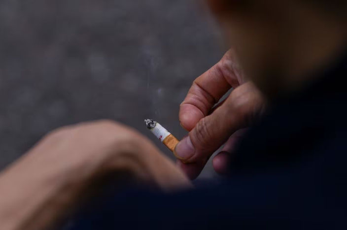 Seorang Pria Memegang Sebatang Rokok di Tangannya di London, Inggris (Reuters/Maja Smiejkowska)