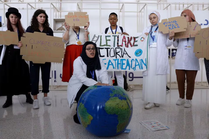 Anggota Federasi Internasional Asosiasi Mahasiswa Kedokteran Memegang Plakat Saat Protes Menuntut Diakhirinya Bahan Bakar Fosil pada KTT Iklim Dunia COP28, di Dubai (Reuters/Amr Alfiqy)