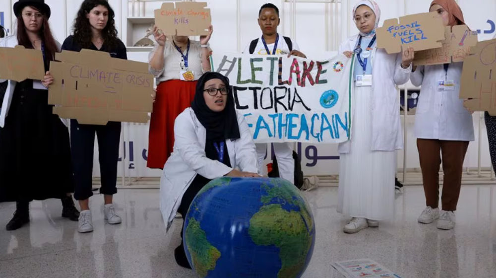 Anggota Federasi Internasional Asosiasi Mahasiswa Kedokteran Memegang Plakat Saat Protes Menuntut Diakhirinya Bahan Bakar Fosil pada KTT Iklim Dunia COP28, di Dubai