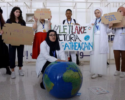 Anggota Federasi Internasional Asosiasi Mahasiswa Kedokteran Memegang Plakat Saat Protes Menuntut Diakhirinya Bahan Bakar Fosil pada KTT Iklim Dunia COP28, di Dubai