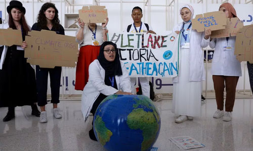 Anggota Federasi Internasional Asosiasi Mahasiswa Kedokteran Memegang Plakat Saat Protes Menuntut Diakhirinya Bahan Bakar Fosil pada KTT Iklim Dunia COP28, di Dubai