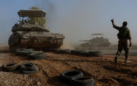 Seorang Tentara Israel Memberi Isyarat Kepada Seorang Awak Tank Saat Melintasi Jalan