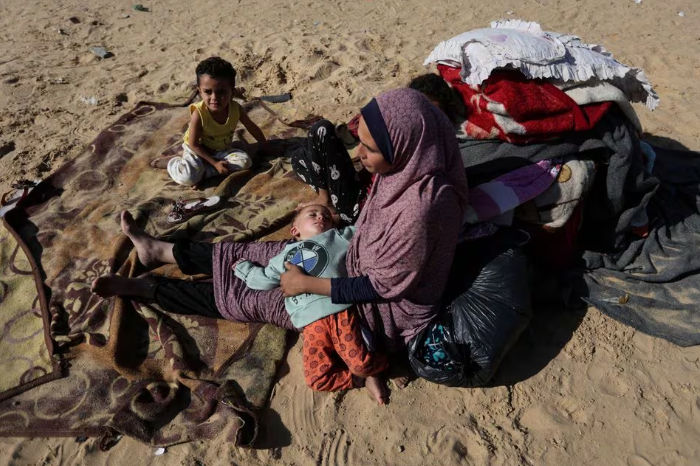 Seorang Wanita Duduk Bersama Anak-Anak di Luar, Sebagai Pengungsi Palestina (Reuters/Ibrahim Abu Mustafa)