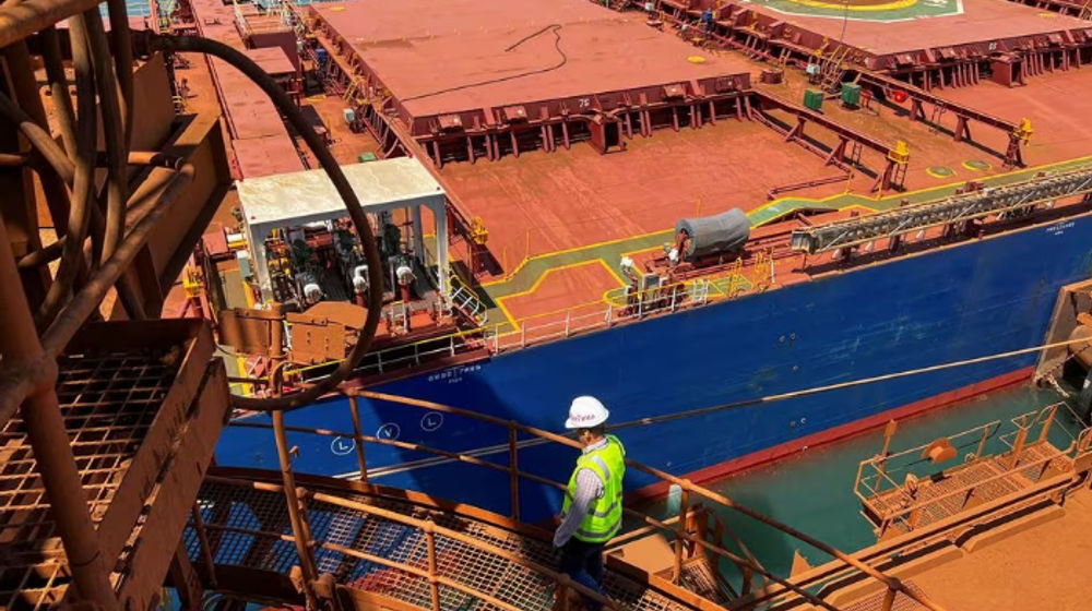 Seorang Pengunjung Berjalan di Depan Pengangkut Bijih Besi di Port Dampier operations Rio Tinto di Australia Barat