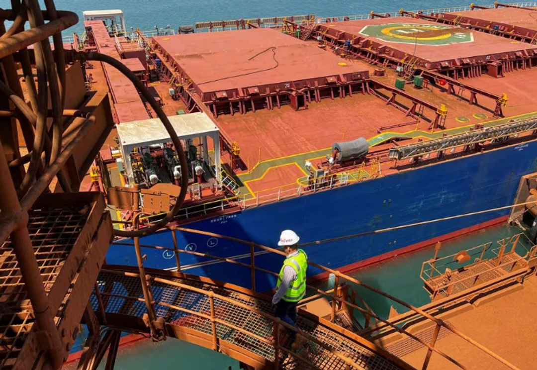 Seorang Pengunjung Berjalan di Depan Pengangkut Bijih Besi di Port Dampier operations Rio Tinto di Australia Barat (Reuters/Melanie Burton)