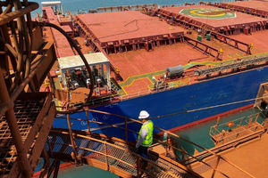 Seorang Pengunjung Berjalan di Depan Pengangkut Bijih Besi di Port Dampier operations Rio Tinto di Australia Barat