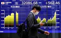 Seorang Pria Berjalan Melewati Monitor Listrik yang Menampilkan Rata-Rata Saham Nikkei Jepang dan Pergerakan Terkini (Reuters/Issei Kato)