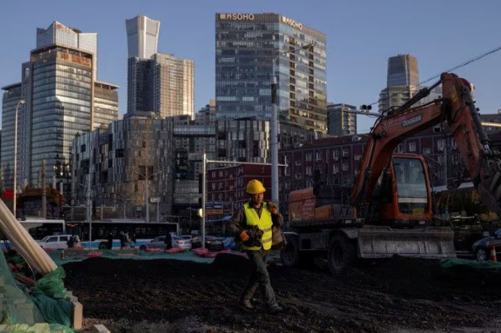 Seorang Pekerja Berjalan Melintasi Lokasi Konstruksi di Kawasan Pusat Bisnis (Reuters/Thomas Peter)