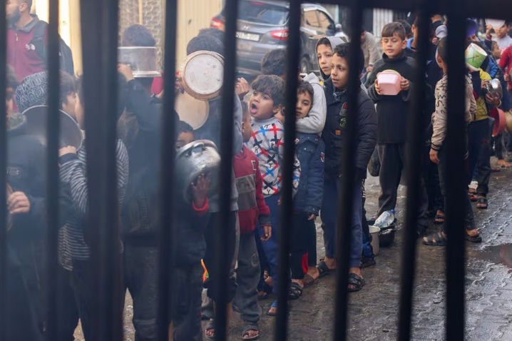Anak-Anak Palestina Membawa Panci Saat Mengantri untuk Menerima Makanan yang Dimasak oleh Dapur Amal, Di Tengah Kekurangan Pasokan Makanan (Reuters/Saleh Salem)
