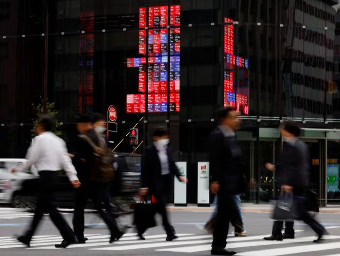 Pejalan Kaki Berjalan Melewati Papan Elektronik yang Menampilkan Harga Saham Berbagai Perusahaan, Di Sebuah Kawasan Bisnis Di Tokyo (Reuters/Kim Kyung-Hoon)