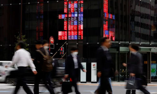 Pejalan Kaki Berjalan Melewati Papan Elektronik yang Menampilkan Harga Saham Berbagai Perusahaan, Di Sebuah Kawasan Bisnis Di Tokyo (Reuters/Kim Kyung-Hoon)