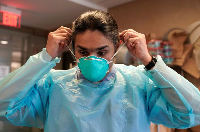 Dr. Syed Naqvi, seorang ahli paru, mengenakan masker N95 sebelum memasuki ICU di Rumah Sakit SSM Health St. Anthony (Reuters/Nick Oxford)
