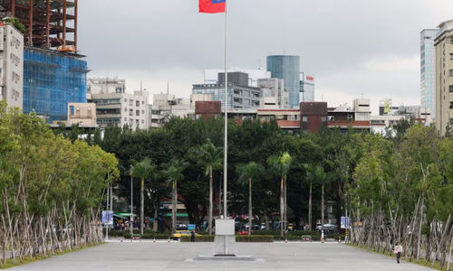 Seseorang berjalan di samping bendera Taiwan yang berkibar di luar Balai Peringatan Sun Yat-Sen di Taipei