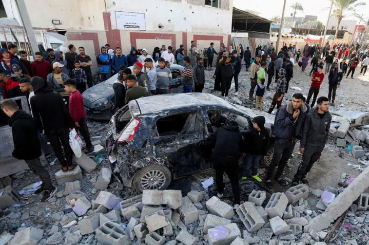 Warga Palestina berkumpul di samping kendaraan yang rusak saat mereka memeriksa lokasi serangan Israel (Reuters/Mohammed Al-Masri)