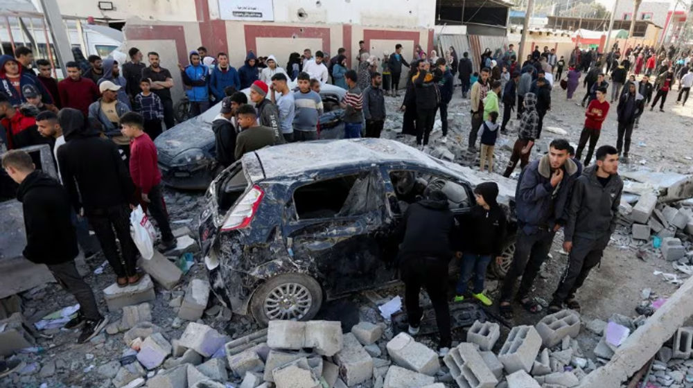 Warga Palestina berkumpul di samping kendaraan yang rusak saat mereka memeriksa lokasi serangan Israel