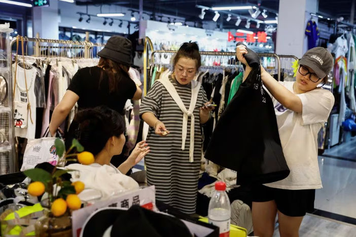 Pelanggan berbelanja pakaian di sebuah kios di dalam pasar grosir di Beijing (Reuters/Tingshu Wang)