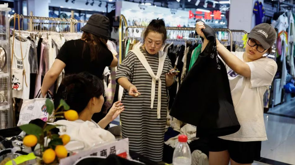 Pelanggan berbelanja pakaian di sebuah kios di dalam pasar grosir di Beijing