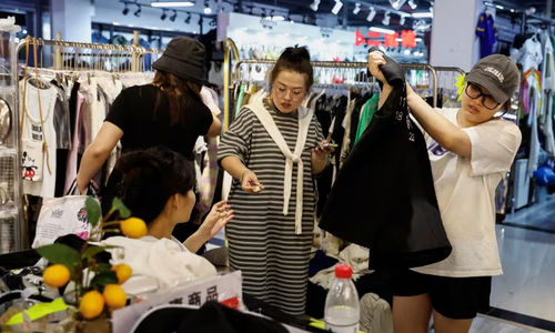 Pelanggan berbelanja pakaian di sebuah kios di dalam pasar grosir di Beijing