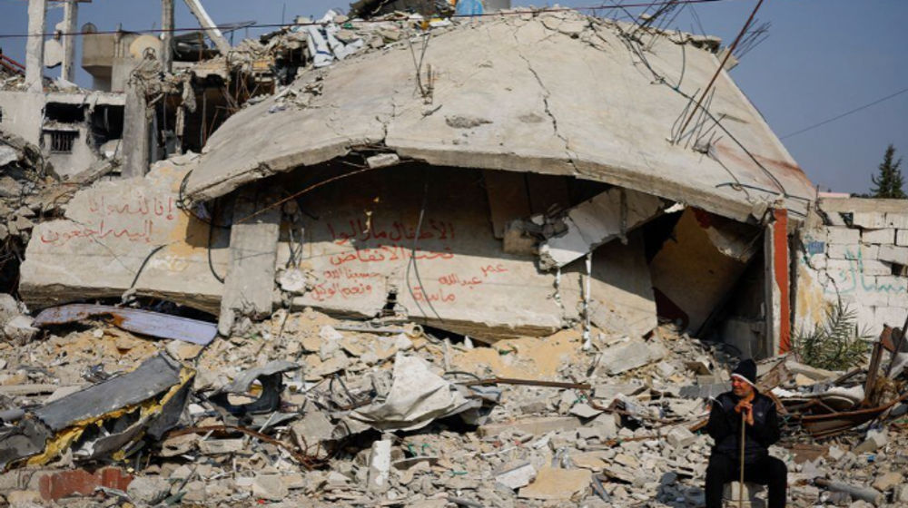 Seseorang duduk di samping tulisan yang dilukis di dinding di tengah puing-puing rumah keluarga, yang hancur dalam serangan mematikan Israel di tengah konflik yang sedang berlangsung antara Israel dan Hamas