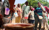 Orang-orang memegang panci saat relawan membagikan makanan di Omdurman, Sudan