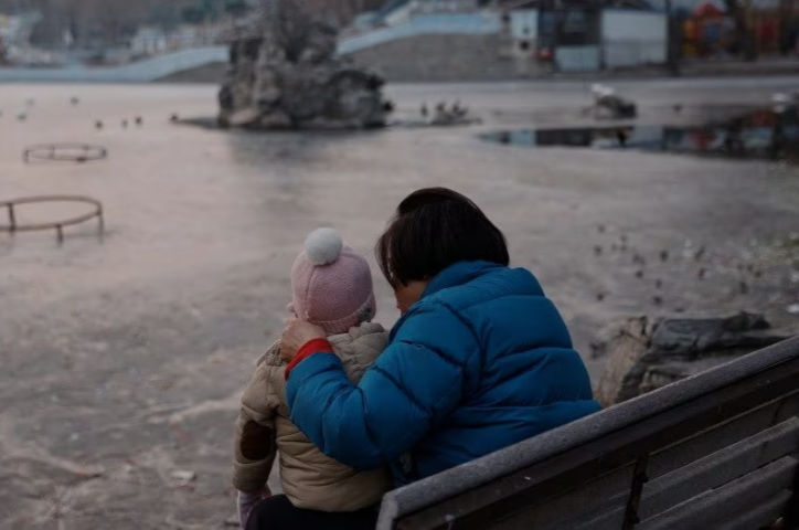 Seorang wanita dan seorang anak duduk di sebuah taman di Beijing (Reuters/Tingshu Wang)