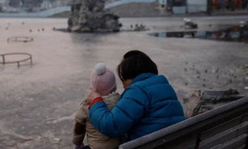 Seorang wanita dan seorang anak duduk di sebuah taman di Beijing (Reuters/Tingshu Wang)