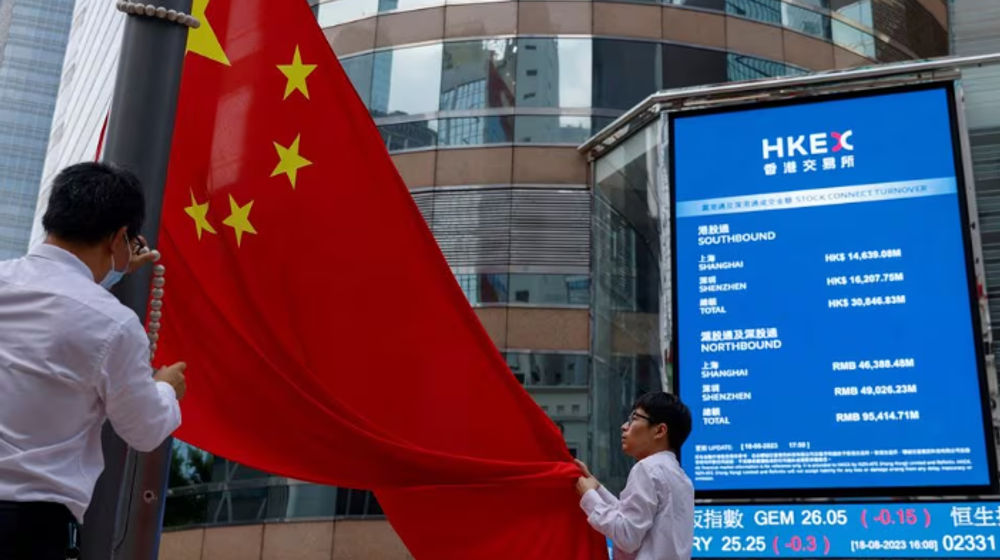 Staf menurunkan bendera nasional China di depan layar yang menampilkan indeks dan harga saham di luar Exchange Square, di Hong Kong, China