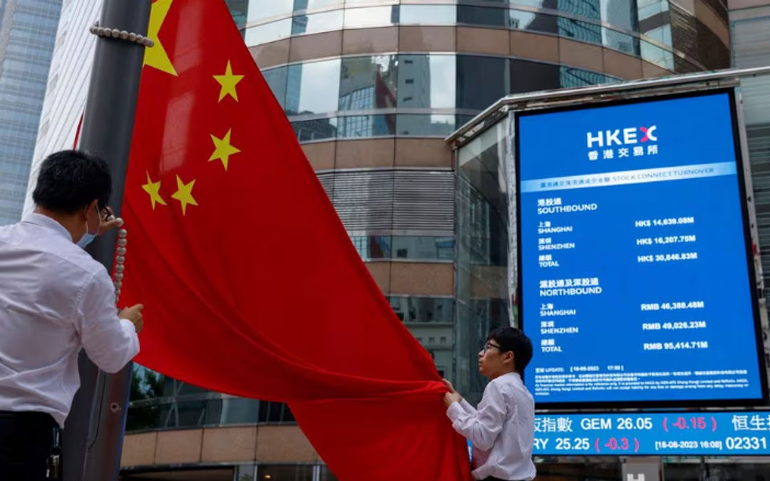 Staf menurunkan bendera nasional China di depan layar yang menampilkan indeks dan harga saham di luar Exchange Square, di Hong Kong, China