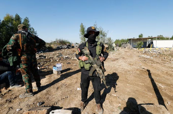 Pejuang kelompok milisi Hizbullah Kataib Irak berdiri di lokasi serangan udara AS, di Hilla, Irak (Reuters/Alaa al-Marjani)