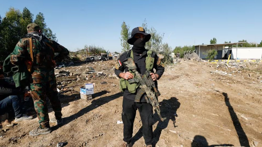 Pejuang kelompok milisi Hizbullah Kataib Irak berdiri di lokasi serangan udara AS, di Hilla, Irak