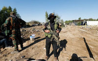 Pejuang kelompok milisi Hizbullah Kataib Irak berdiri di lokasi serangan udara AS, di Hilla, Irak