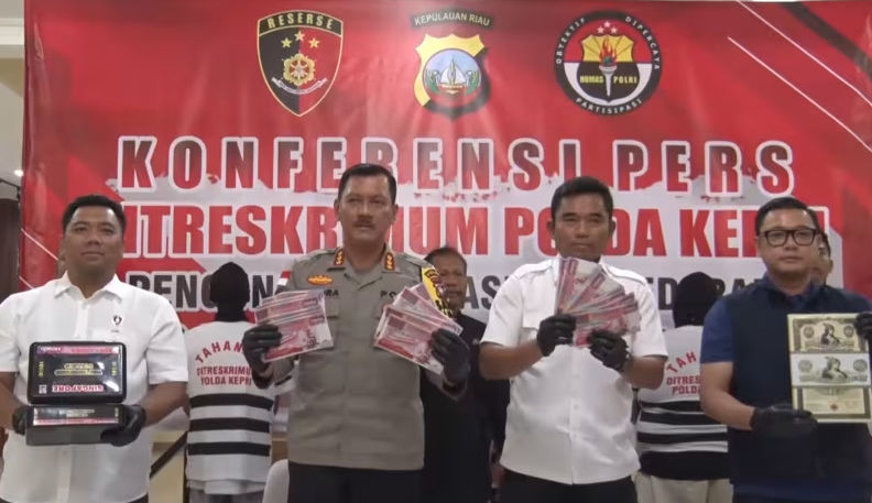  Petugas polisi Indonesia memegang uang kertas palsu setelah menangkap sindikat pada November 2023. (Facebook / Polda Kepri)
