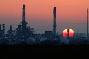 Matahari terbenam di balik cerobong asap kilang minyak Total Grandpuits, tenggara Paris
