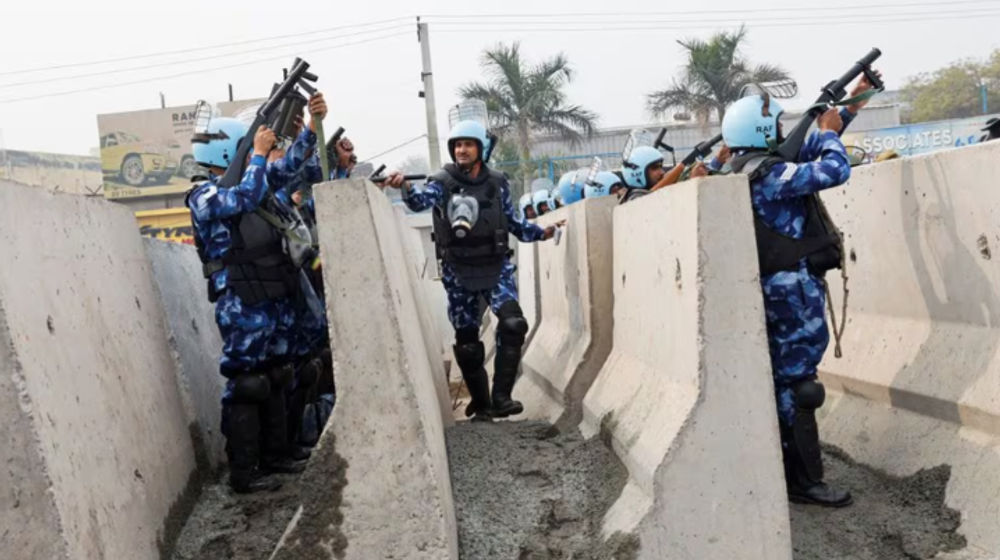 Petugas polisi mengangkat senjata saat barikade didirikan di jalan raya nasional untuk menghentikan para petani