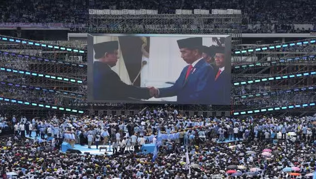 Presiden Indonesia Joko Widodo, berjabat tangan dengan calon presiden Prabowo Subianto ditampilkan di layar lebar saat kampanye kampanye Prabowo di Stadion Utama Gelora Bung Karno (AP)