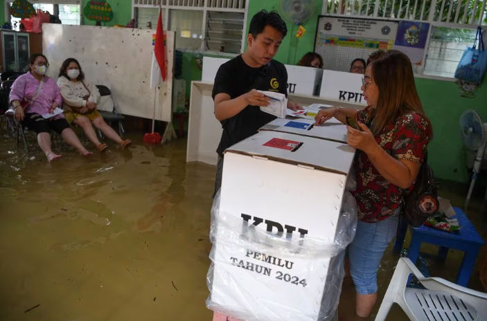 Para pemilih memberikan suaranya di TPS yang kebanjiran saat pemilihan umum di Jelambar, Jakarta Barat (Reuters/Wahyu Putro A)