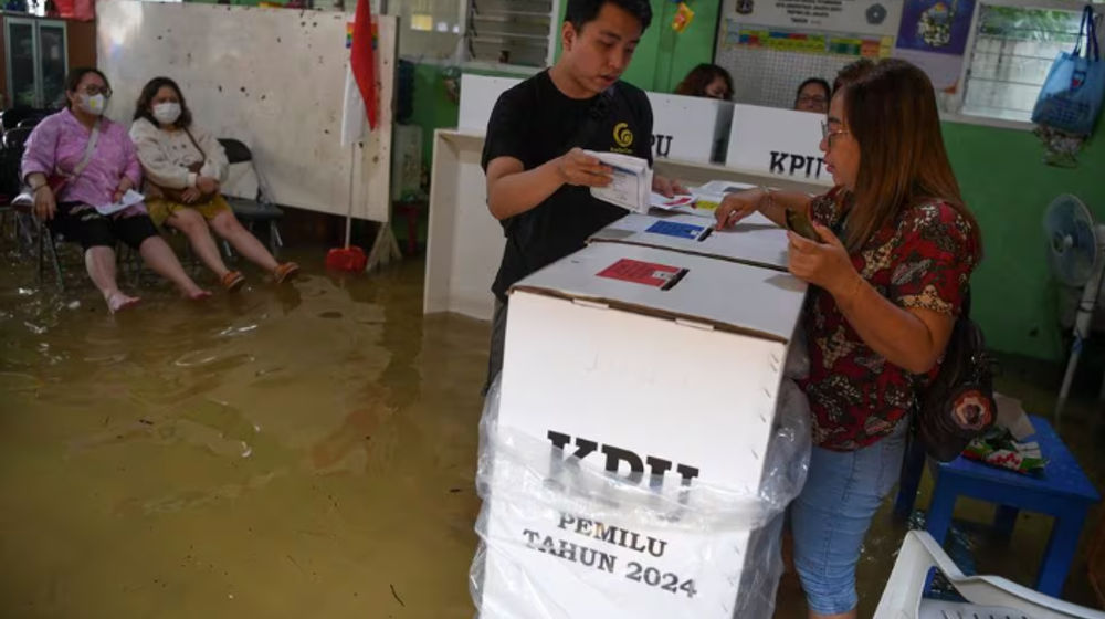 Para pemilih memberikan suaranya di TPS yang kebanjiran saat pemilihan umum di Jelambar, Jakarta Barat