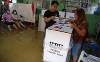 Para pemilih memberikan suaranya di TPS yang kebanjiran saat pemilihan umum di Jelambar, Jakarta Barat