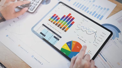 Foto seorang pebisnis menggunakan tablet untuk menganalisis grafik statistik strategi keuangan perusahaan.