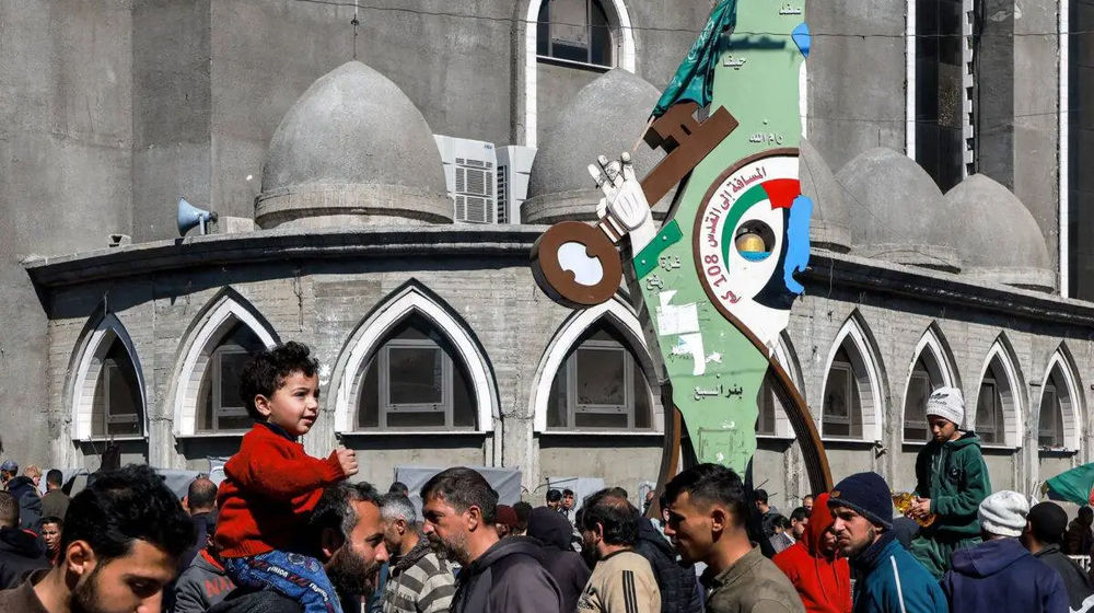 Orang-orang berjalan melewati papan tanda yang menggambarkan peta bersejarah Palestina