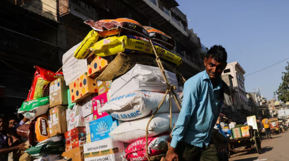 Seorang buruh mengangkut gerobak penuh karung di pasar grosir di kawasan tua Delhi, India