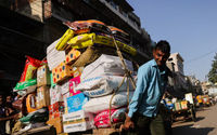 Seorang buruh mengangkut gerobak penuh karung di pasar grosir di kawasan tua Delhi, India
