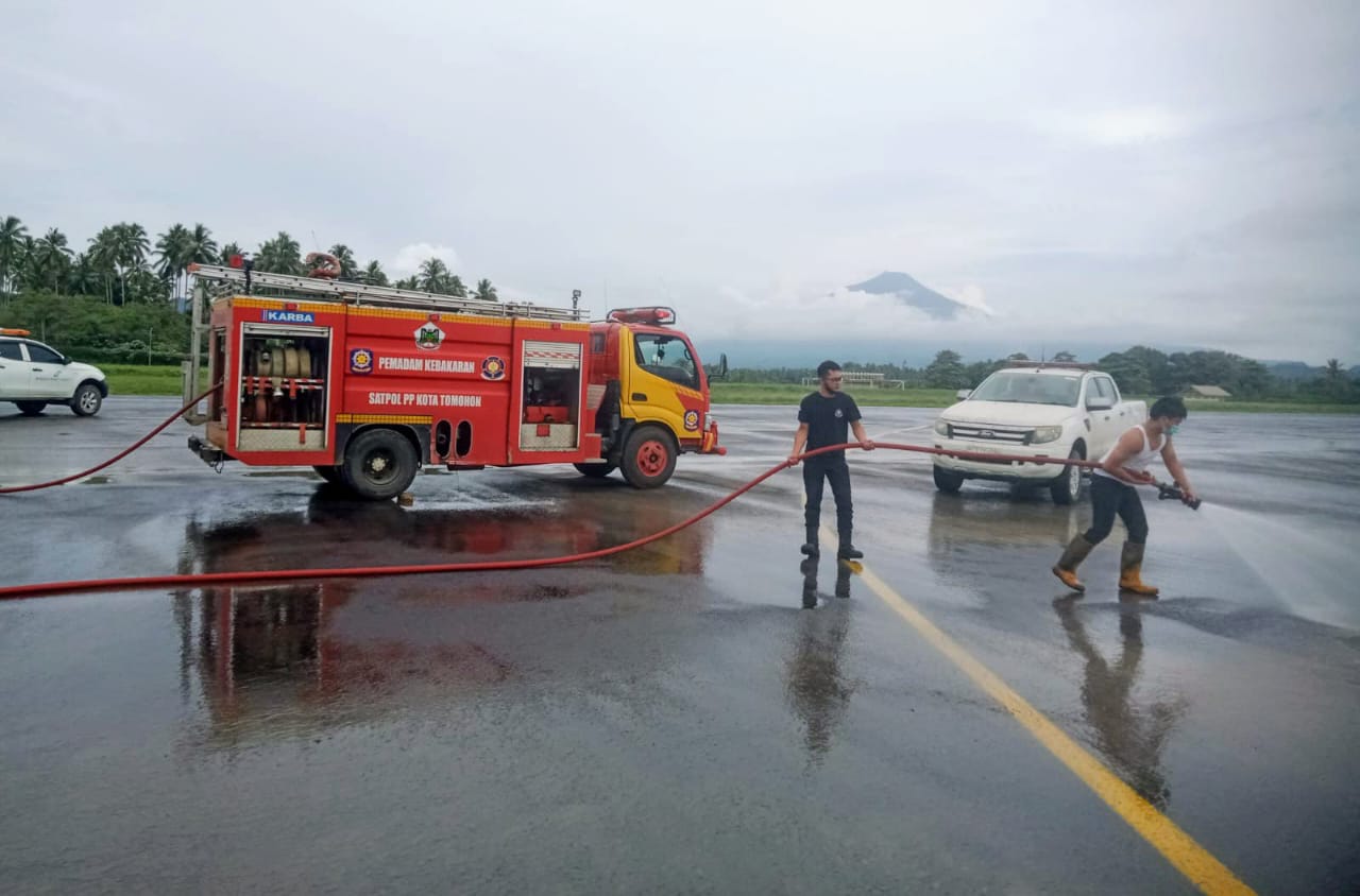 Tim Damkar Satuan Polisi Pamong Praja (Sat Pol PP) Daerah Kota Tomohon saat melakukan pembersihan di landasan Bandara Internasional Sam Ratulangi Manado (Foto: Istimewa)