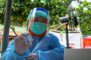 Potret petugas kesehatan memegang vaksin.