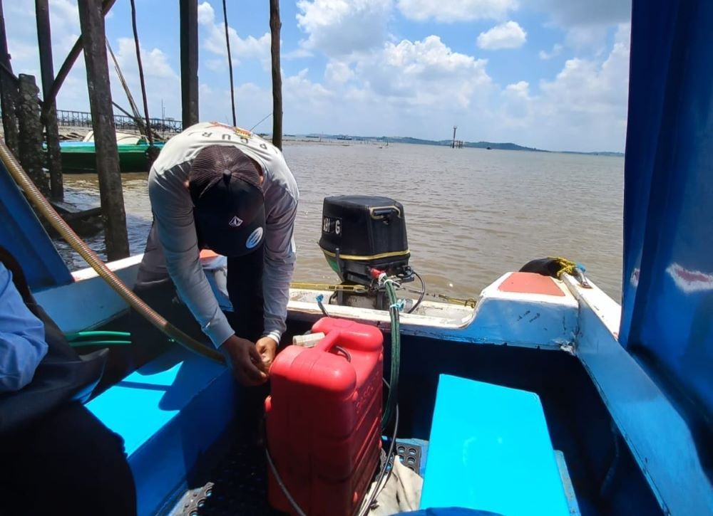 Seorang motoris di  Kabupaten Penajam Paser Utara menuangkan selang ke dalam wadah. Kesulitan BBM dirasakan nelayan dan pengelola transportasi  laut di Kaltim.    