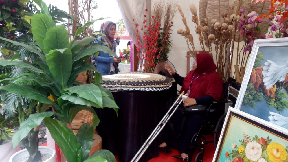 Bunda Gendhis melayani pengunjung stand dari kursi rodanya