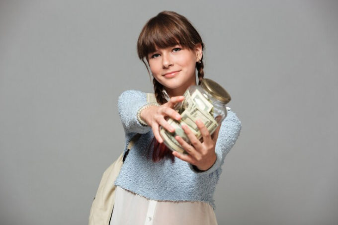 Perempuan memegang jar berisi uang.