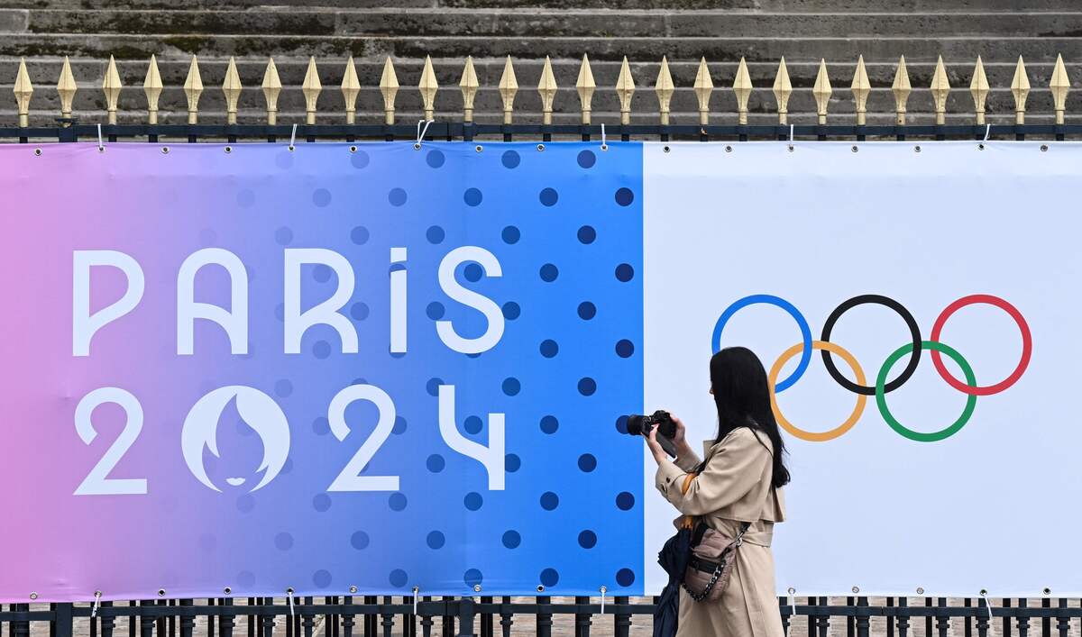 
Seorang pengamat memotret spanduk Olimpiade Paris 2024 di luar gedung Majelis Nasional di Paris, Prancis.