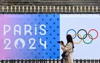 
Seorang pengamat memotret spanduk Olimpiade Paris 2024 di luar gedung Majelis Nasional di Paris, Prancis.