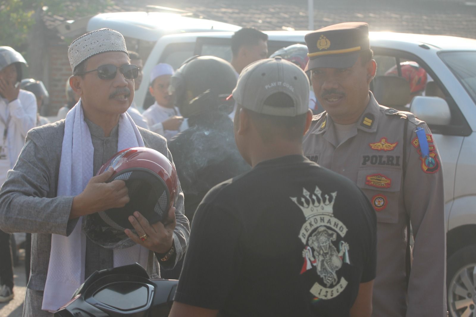 Kepala Sekolah SMAN 1 Krembung Suswanto hendak mengenakan helm kepada pengguna jalan.